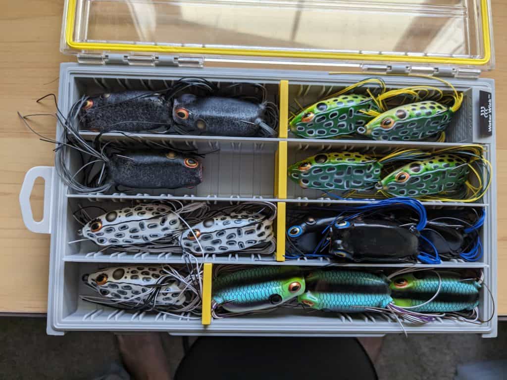 A variety of colorful Booyah Pad Crashers neatly organized in a Plano Edge box, ready to deliver an unparalleled fishing experience.