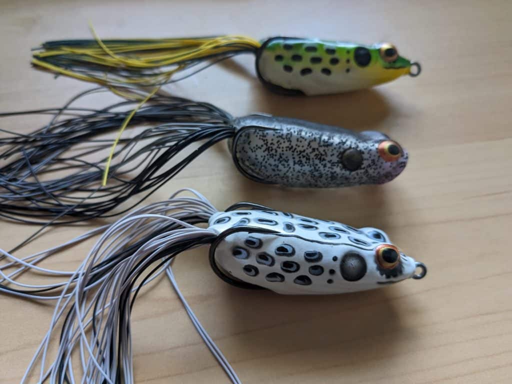 Three vivid Booyah Pad Crashers in striking Albino, Ole Smokey, and Bullfrog colors, promising a thrilling bass fishing experience.