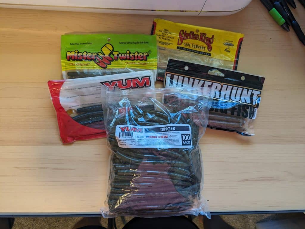 An image showcasing a diverse selection of stick worm brands, including Yum, Strike King, and Lunkerhunt, all ideal for creating a successful wacky rig for bass fishing.