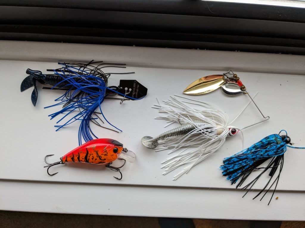 Collection of top lures – spinnerbait, chatterbait, squarebill, and football jig – perfectly suited for bass fishing after a storm.