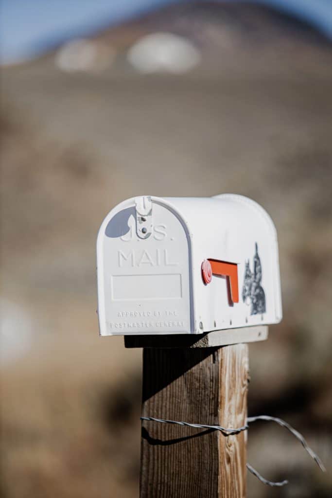 Angler placing a handwritten letter into a landowner's mailbox, seeking permission for private pond fishing access