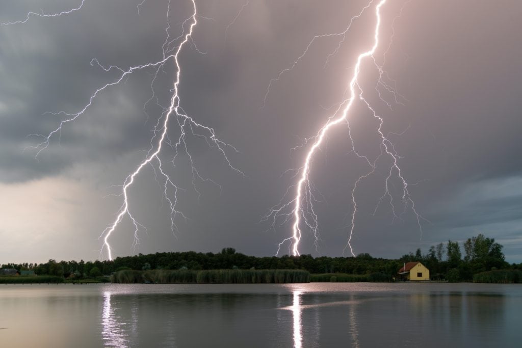 Angler casting a line on a serene lake, capitalizing on prime bass activity after a storm.