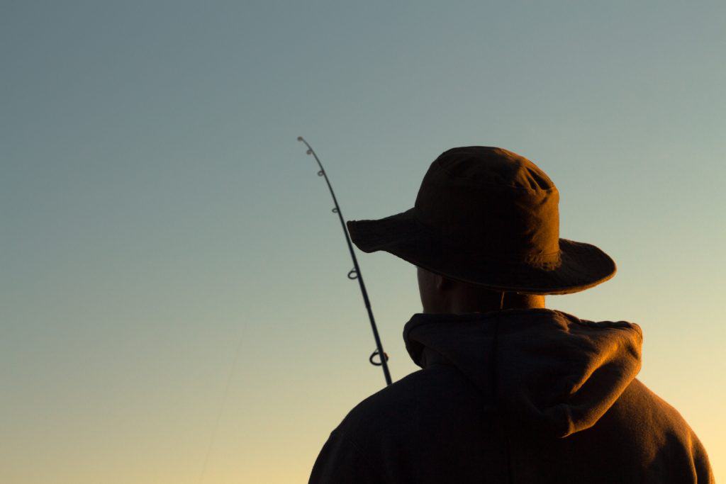 Solo angler casting a line in a tranquil private pond after securing fishing permission.