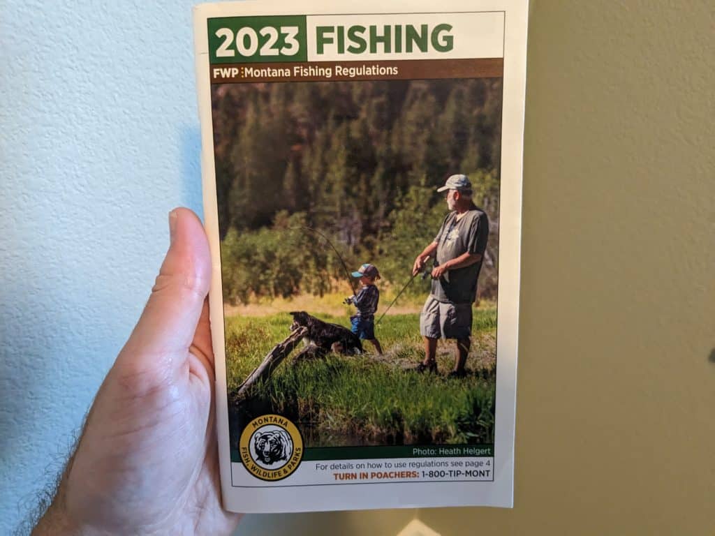 Close-up of a state fishing guidebook opened to a page about pond bass habitats, providing insights on identifying bass-filled waters.