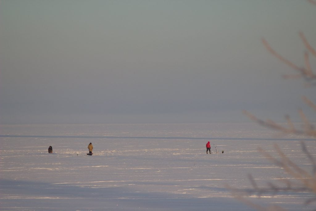 Group of anglers ice fishing for bass on a frozen lake