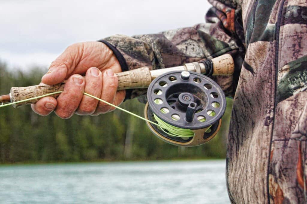 Man holding fly fishing rod and reel ready to go fly fishing for bass